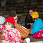 group of people sitting together talking on the floor wearing warm clothing