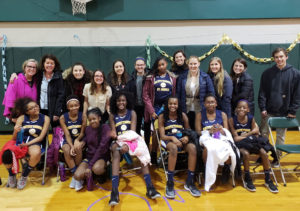 group of basketball players and smc volunteers posing for a picture in a gym