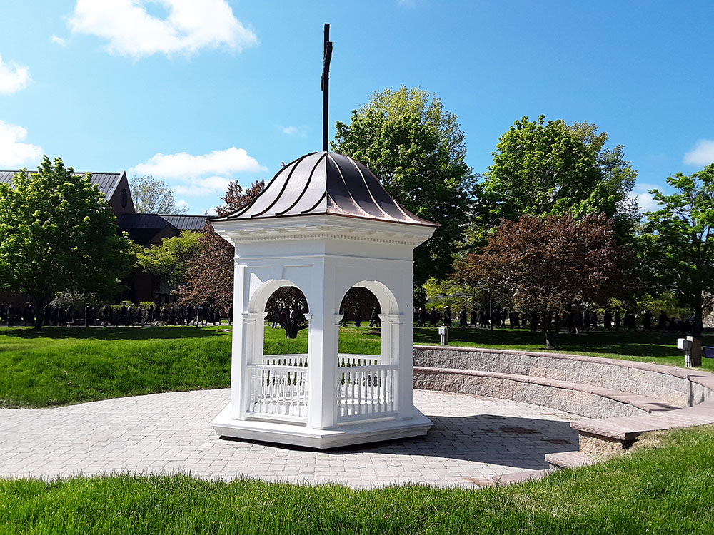 The Class of 2023 in procession to Commencement Sunday in the background with the Founders Hall Cupola, newly placed this year, in the foreground. (Photo Mark Tarnacki)